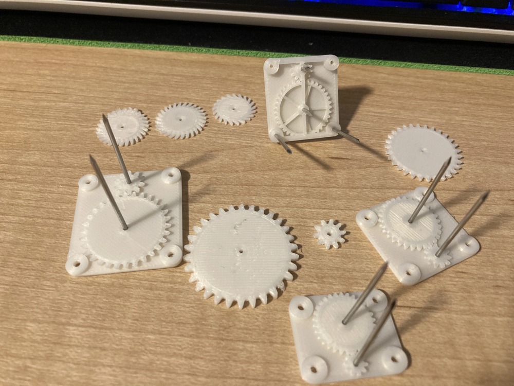 Printed gears and escapement test pieces laid out for comparison